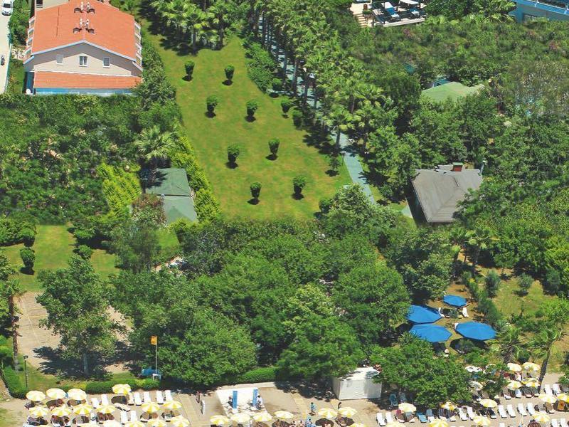 Hotelanlage mit mehreren Gebäuden, großem Pool und Sandstrand mit Sonnenliegen am Meer.