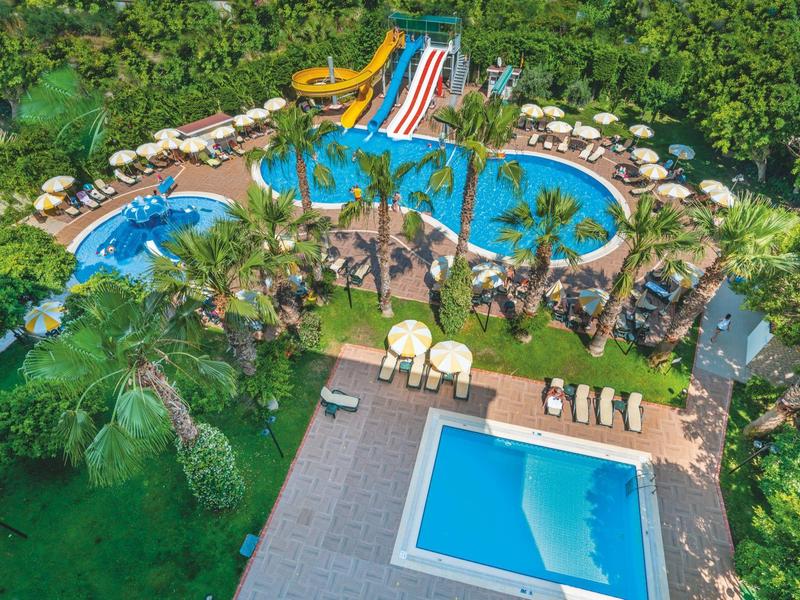 Großer Poolbereich mit Wasserrutschen, Palmen und Liegestühlen in einem tropischen Resort.