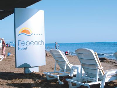 Strand mit weißen Liegestühlen, blauem Himmel und Meer, Schild mit Schrift "Febeach hotel".