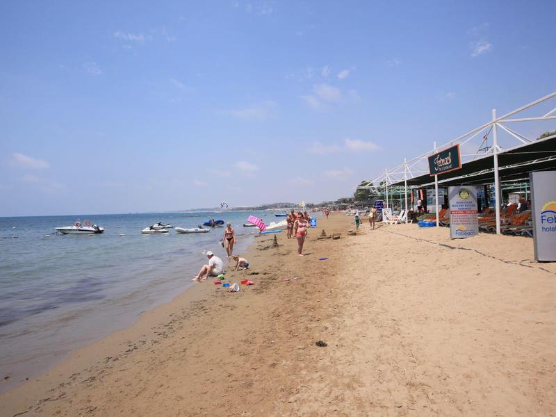 Beach with sandy shore, people relaxing by the water and near beach facilities.