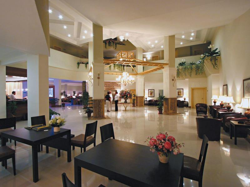 Spacious hotel lobby with seating areas, central floral arrangement, and bright lighting.