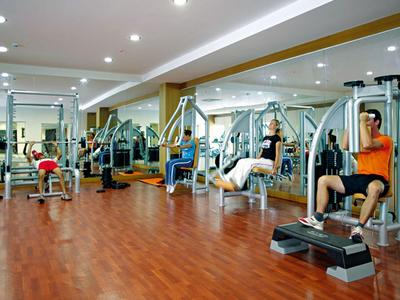 Palestra moderna con pavimento in legno, varie attrezzature per esercizi e luci a soffitto.