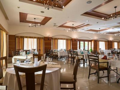 Spacious hotel dining room with round tables, wooden chairs, and bright natural light.