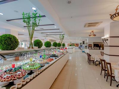 Spacious hotel dining area with buffet table featuring desserts and green floral decorations.