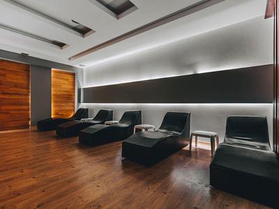 Modern lounge with black leather chairs, wooden floor, and ambient wall lighting.