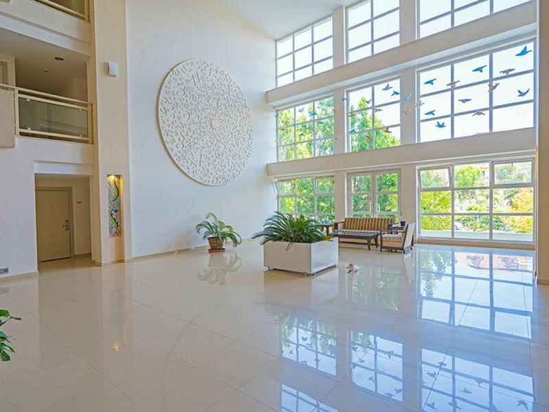Bright hotel lobby with large windows, plants, seating, and minimalist decor.