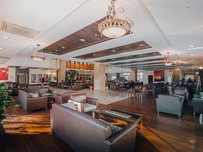 Spacious hotel lounge with modern sofas, wooden floor, and elegant lighting fixtures.