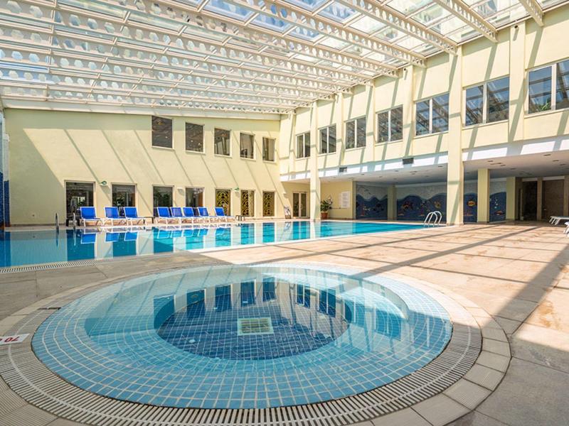 Indoor courtyard with circular hot tub and glass ceiling allowing sunlight