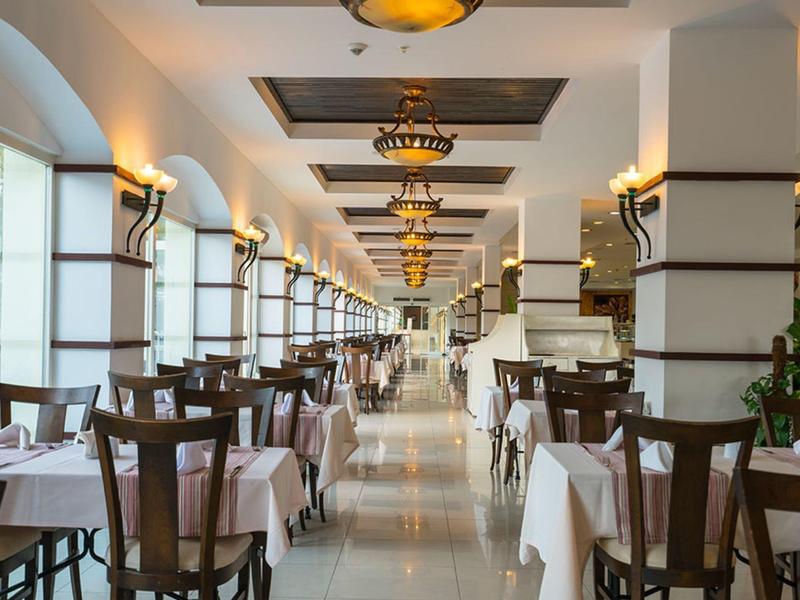 Spacious restaurant with neatly arranged wooden chairs and tables covered in white cloths.