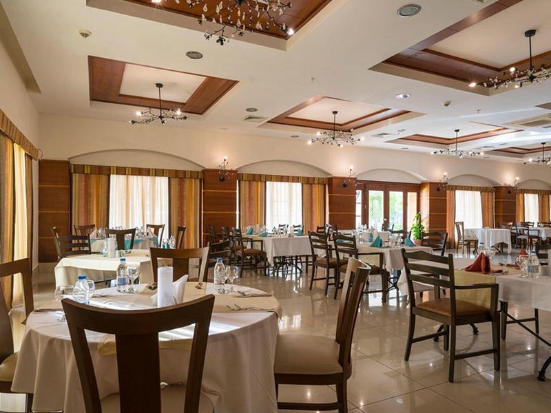 Spacious hotel dining room with round tables, wooden chairs, and bright natural light.
