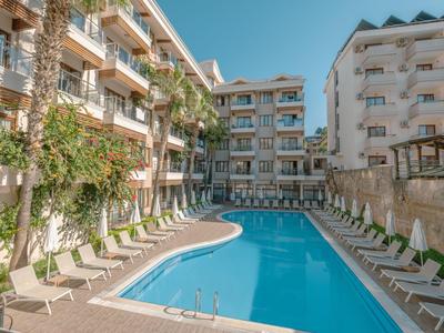 Piscina moderna dell'hotel con lettini ai lati, circondata da hotel su più piani e palme.
