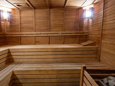 Interno di una sauna in legno con panche su più livelli e illuminazione a parete.