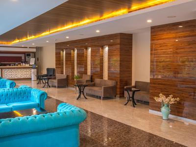 Moderna hall d'hotel con divani blu, pannelli in legno e tavoli eleganti.