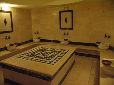 Tradizionale hammam turco con piattaforma centrale in pietra e lavandini lungo le pareti.