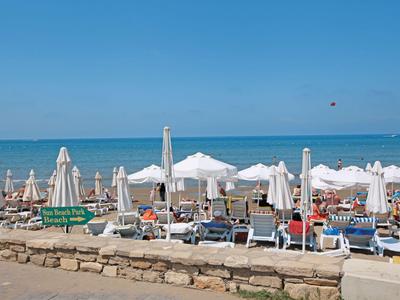 Area sulla spiaggia con lettini, ombrelloni e vista sul mare con cielo limpido.