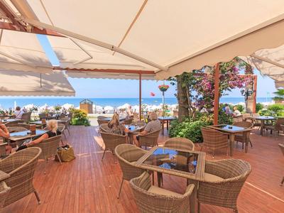 Terrazza aperta di un hotel con posti a sedere e vista mare sotto ombrelloni.