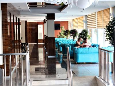 Lobby d'hotel luminosa con divani blu, grandi finestre e dettagli moderni in legno.