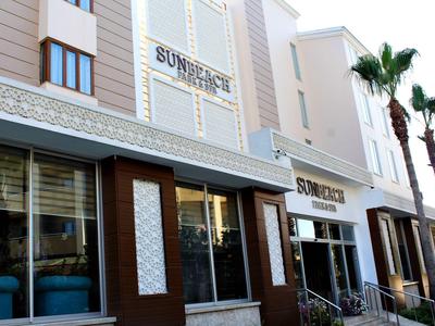 Vista esterna di un edificio con l'insegna Sun Beach e palme accanto.