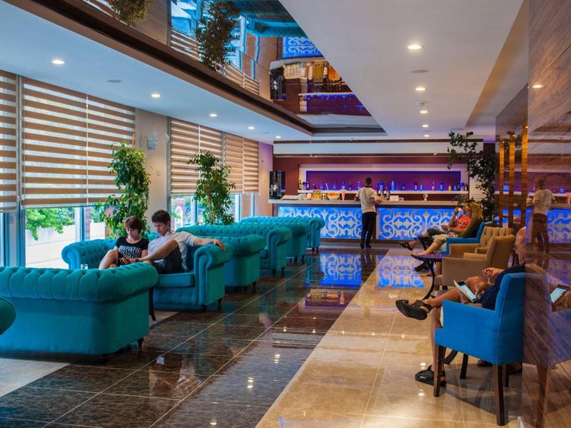 Hall dell'hotel arredato modernamente con divani blu e area bar sullo sfondo