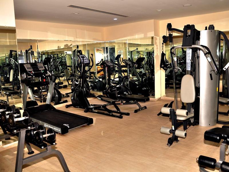 Palestra luminosa con macchinari per l'allenamento e grandi specchi alle pareti.