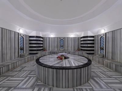 Hammam moderno con paredes de mármol y mesa redonda central.