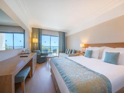 Chambre d'hôtel moderne avec lit double, bureau, chaise et vue sur l'extérieur par la fenêtre.