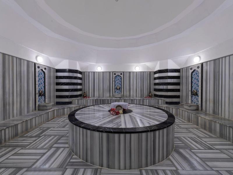 Hammam moderno con paredes de mármol y mesa redonda central.