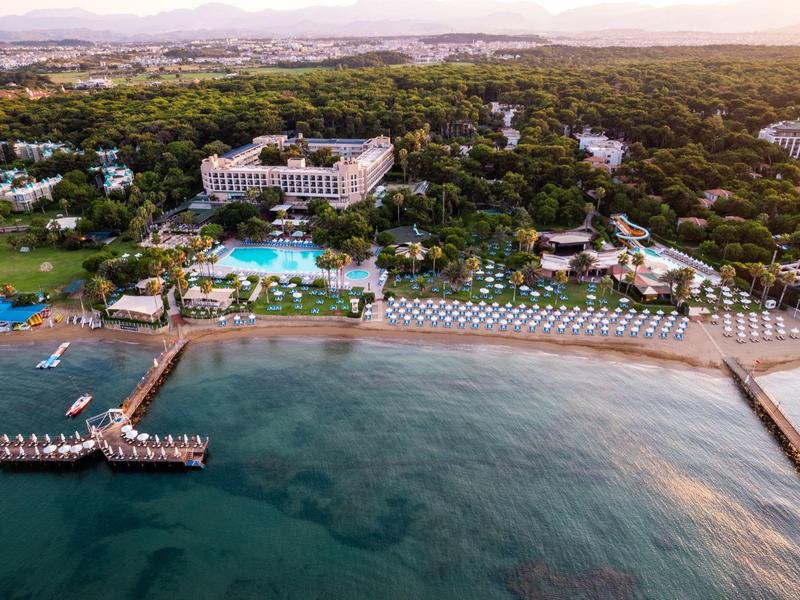 Vista aérea de un resort con piscina, playa y muelles de madera en el mar al atardecer.