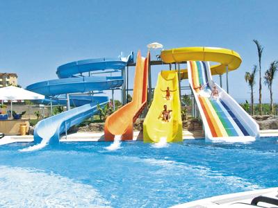 Buiten barbecueplek met houten overkapping naast een betegeld pad en palmbomen.