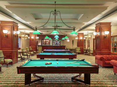 Grote speelkamer met meerdere pooltafels en comfortabele zitplaatsen bij warm licht.