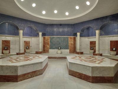 Ruime ronde kamer met marmeren banken en decoratieve muren, voorzien van zachte plafondverlichting.