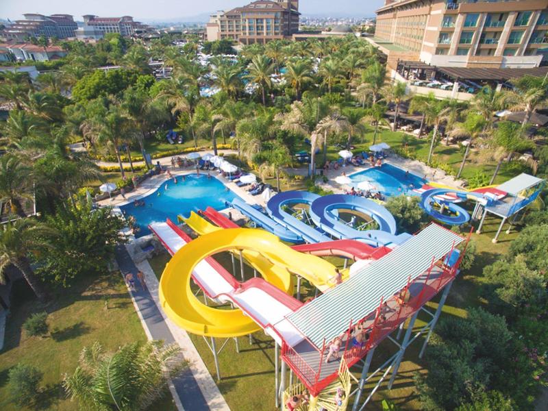 Resort met glijbanen, zwembaden en groene omgeving bij een hotelgebouw.