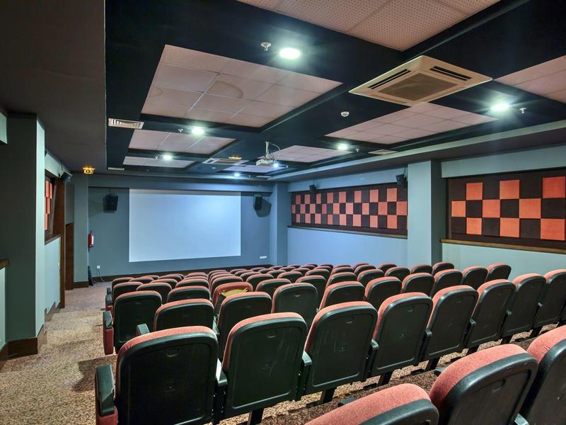 Kleine conferentieruimte van hotel met rijen stoelen en een projectiescherm.