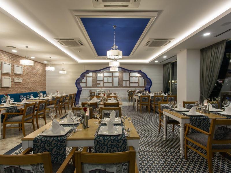 Elegancka jadalnia hotelowa z drewnianymi stołami i starannie urządzonym wnętrzem.