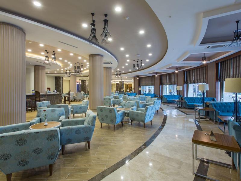 Nowoczesne wnętrze salonu hotelowego z niebieskimi fotelami i ciepłym oświetleniem.