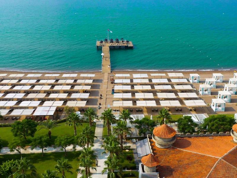 Widok z lotu ptaka na plażę z pomostem i białymi kabinami.