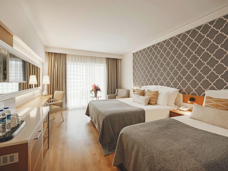 Pokój hotelowy z dwoma dużymi łóżkami, nowoczesnym wystrojem i dużą ilością naturalnego światła.