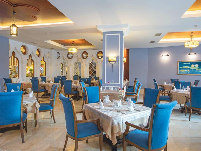 Elegancka sala restauracyjna z niebieskimi krzesłami i przygotowanymi stołami, jasna i przyjazna atmosfera.