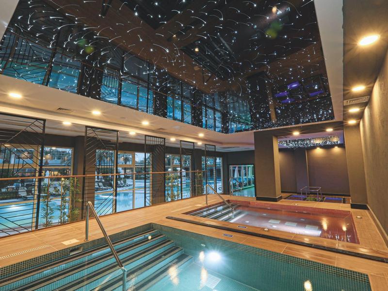 Podgrzewany basen kryty z gwiaździstym sufitem i jacuzzi w nowoczesnym hotelu.
