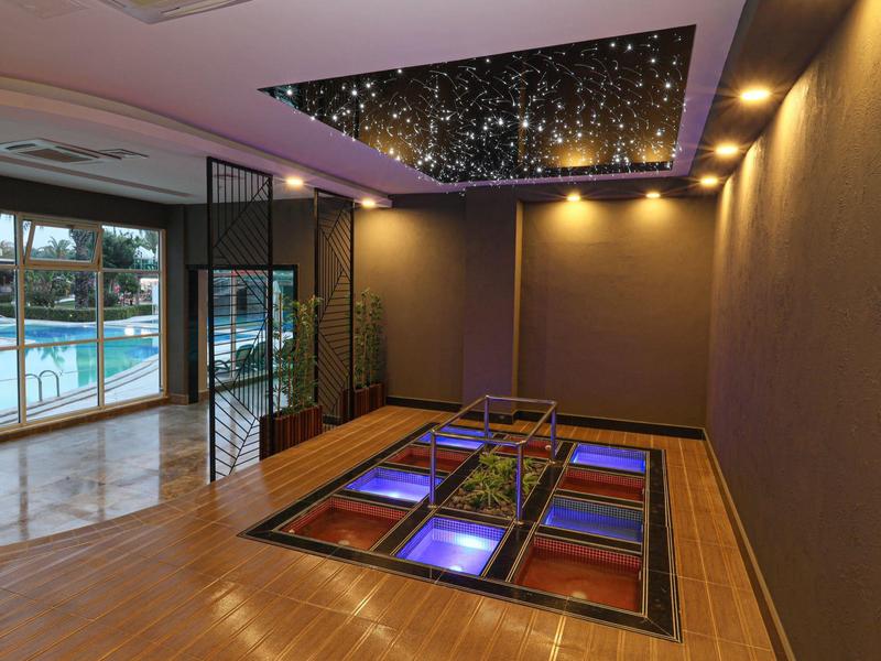 Nowoczesna przestrzeń z wewnętrznym basenem i gwiaździstym sufitem nad jasną podłogą.