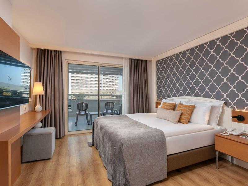 Nowoczesny pokój hotelowy z łóżkiem podwójnym, balkonem i telewizorem.