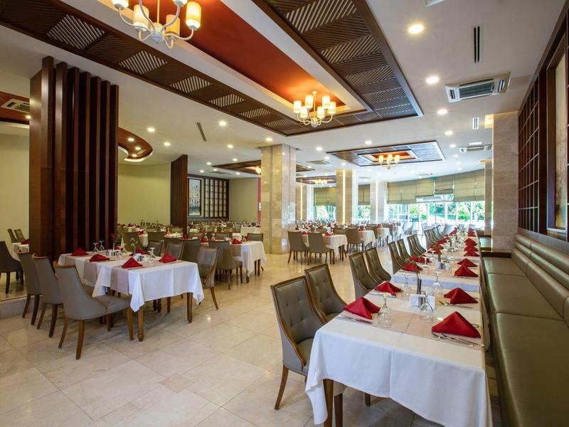 Elegancka jadalnia hotelowa z nakrytymi stołami i szarymi krzesłami.