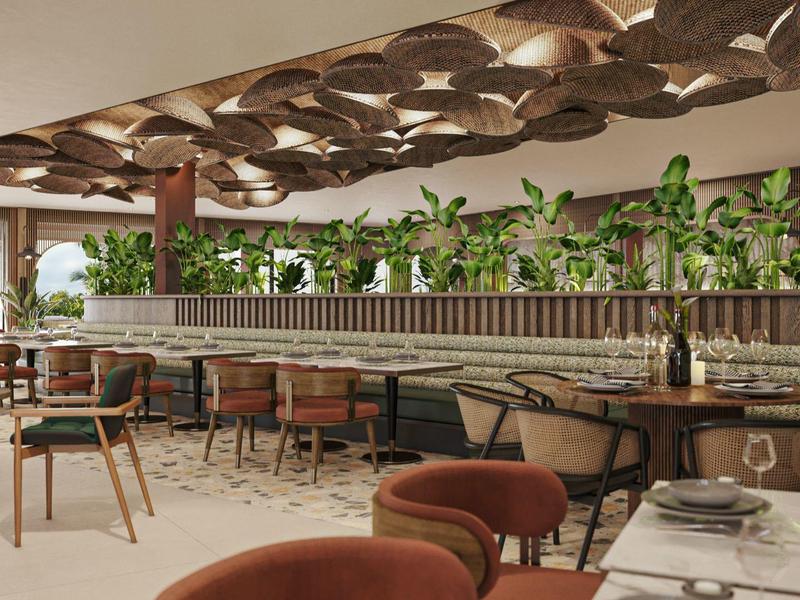 Área de restaurante de hotel diseñado modernamente con muebles de madera y cuero y plantas a lo largo de una pared.