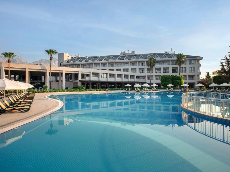 Gran piscina de hotel con tumbonas y cielo despejado al fondo.