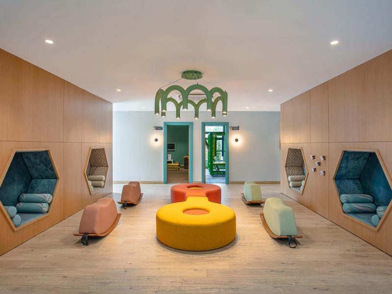 Área moderna de recepción de hotel con asientos coloridos y paneles de madera en las paredes.