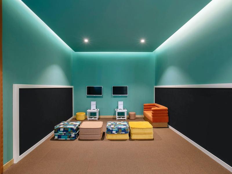 Sala de fitness moderna con esterillas de colores y pequeños monitores en las paredes.