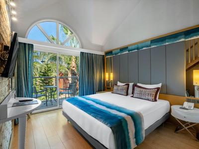 Habitación de hotel moderna con grandes ventanas y balcón, luminosa con cama doble.