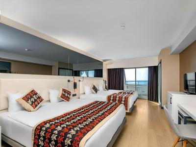 Habitación de hotel moderna con dos camas y vista al mar desde el balcón.