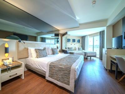 Habitación de hotel espaciosa con cama grande, suelo de madera y decoración neutra moderna.