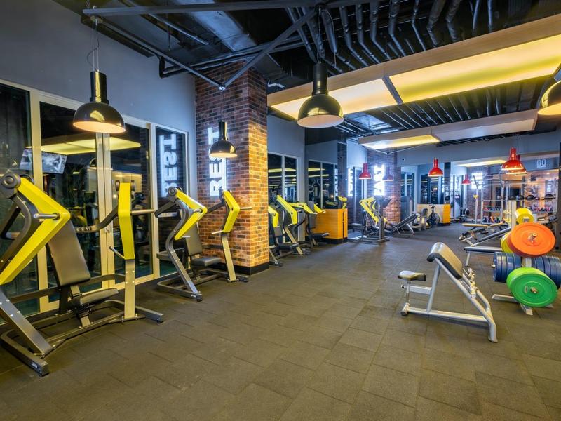 Gimnasio moderno con máquinas de fuerza, pesas y barras en un hotel.